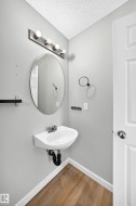 Pedestal sink with chrome faucet, complemented by an oval mirror and a five-bulb vanity light fixture - 