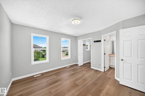 Spacious room featuring wood-finish flooring, light grey walls, and two white-framed windows - 203 84 Street Sw, Edmonton, AB - Indoor Photo Showing Other Room