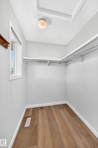 Walk-in closet with wood-finish flooring, white baseboards, and built-in shelving - 203 84 Street Sw, Edmonton, AB - Indoor With Storage