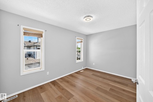 Bright interior space featuring light gray walls and wood-finish flooring - 203 84 Street Sw, Edmonton, AB - Indoor Photo Showing Other Room