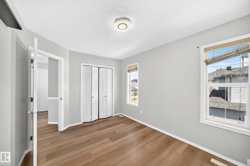 Neutral gray walls complement wood-finish flooring - 203 84 Street Sw, Edmonton, AB - Indoor Photo Showing Other Room