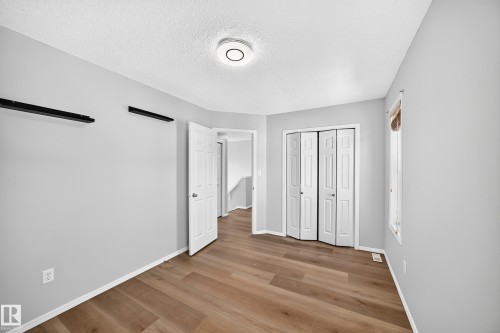 Spacious room featuring wood-finish flooring, light grey painted walls, white trim, and a ceiling-mounted light fixture - 203 84 Street Sw, Edmonton, AB - Indoor Photo Showing Other Room