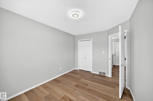 Room featuring wood-finish flooring, light gray walls, white baseboards, and a ceiling-mounted light fixture - 203 84 Street Sw, Edmonton, AB - Indoor Photo Showing Other Room