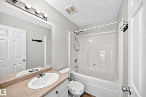 Bathroom featuring a white vanity with a tan countertop, an integrated sink with a chrome faucet, and a large wall-mounted mirror - 203 84 Street Sw, Edmonton, AB - Indoor Photo Showing Bathroom