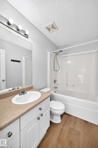 Bathroom featuring a white vanity with an integrated oval sink, a light-toned countertop, and wood-finish flooring - 203 84 Street Sw, Edmonton, AB - Indoor Photo Showing Bathroom