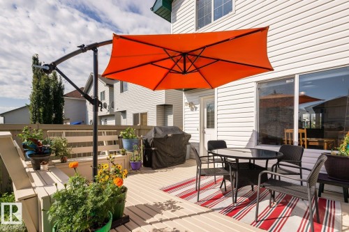Multi-level wood deck featuring a built-in bench, white vinyl siding, and a sliding glass door - 203 84 Street Sw, Edmonton, AB - Outdoor With Deck Patio Veranda With Exterior