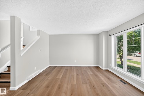Bright living area featuring wood-finish flooring, light gray wall paint, and white trim - 203 84 Street Sw, Edmonton, AB - Indoor Photo Showing Other Room