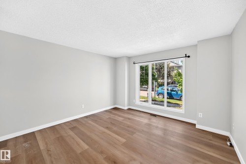 Spacious room featuring wood-finish flooring and light gray painted walls - 203 84 Street Sw, Edmonton, AB - Indoor Photo Showing Other Room