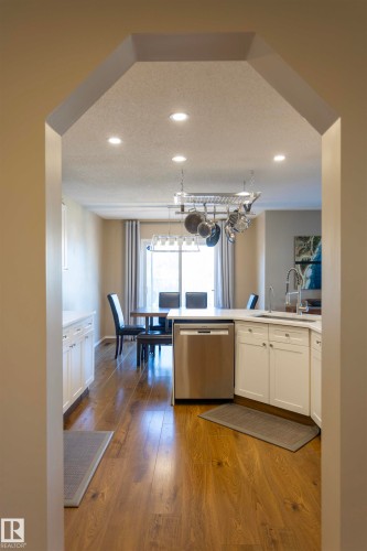 Archway entry featuring recessed lighting, wood-finish flooring, white cabinetry, and a stainless steel dishwasher - 3575 Mclean Crescent Sw, Edmonton, AB 