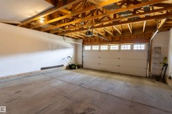 Concrete flooring with exposed ceiling joists, an automatic garage door opener, and a garage door with transom windows - 