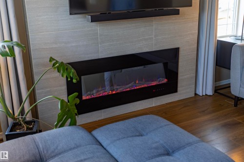 Wall-mounted electric fireplace set into a large-format tiled surround - 3575 Mclean Crescent Sw, Edmonton, AB 
