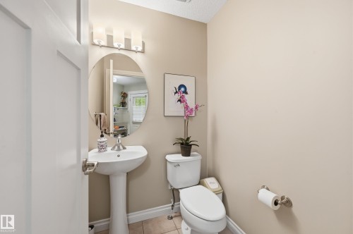 Pedestal sink with an oval mirror, three-light vanity fixture, and tiled flooring - 1111 176 Street Sw, Edmonton, AB 
