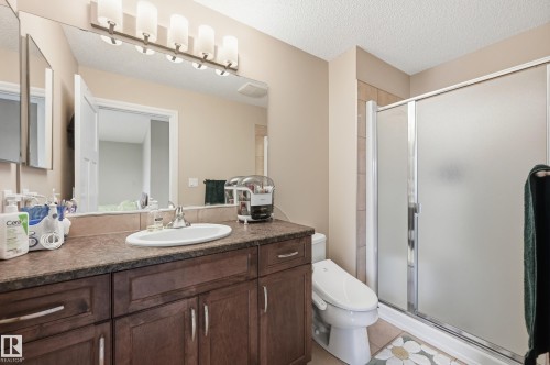 Vanity with wood-finish cabinetry, integrated sink, and dark countertop - 1111 176 Street Sw, Edmonton, AB 