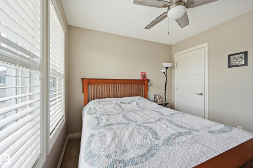White window blinds, wood-finish headboard, neutral wall color, contemporary ceiling fan, and white interior door - 1111 176 Street Sw, Edmonton, AB 