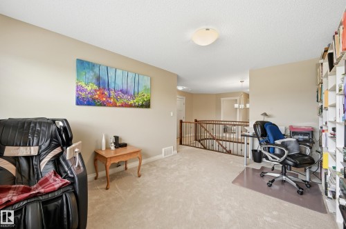 Neutral-toned wall paint, carpeted flooring, built-in shelving, and a wood railing with metal spindles - 1111 176 Street Sw, Edmonton, AB 