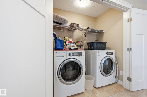 Dedicated laundry space featuring a front-load washer and dryer, wire shelving, and tiled flooring - 1111 176 Street Sw, Edmonton, AB 