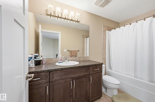 Vanity with integrated sink, dark wood-finish cabinetry, and stone-finish countertop - 1111 176 Street Sw, Edmonton, AB 