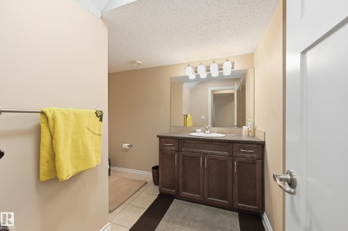 Vanity with an integrated sink, dark wood-finish cabinetry, and a large wall-mounted mirror - 1111 176 Street Sw, Edmonton, AB 