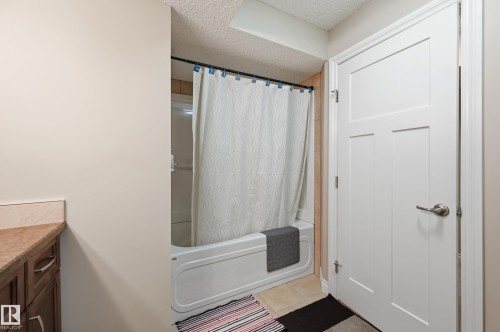 Built-in vanity with wood-finish cabinetry, light-toned countertop, and undermount sink - 1111 176 Street Sw, Edmonton, AB 