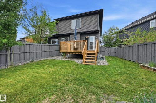 Expansive backyard with manicured lawn, full privacy fencing, and a raised wooden deck with stairs - 1111 176 Street Sw, Edmonton, AB 