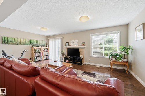 Recessed ceiling lighting, wood-finish flooring, a fireplace with a mantel, a large window with blinds, and a sliding glass door - 1111 176 Street Sw, Edmonton, AB 