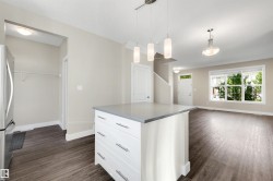 Kitchen island with stone countertop, suspended pendant lighting, wood-finish flooring, and a large window - 