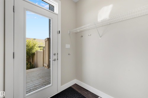 Full-light glass panel door with transom, wood-finish flooring, and wall-mounted wire shelving with integrated hooks - 2125 24 Street Nw, Edmonton, AB 