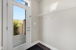Full-light glass panel door with transom, wood-finish flooring, and wall-mounted wire shelving with integrated hooks - 