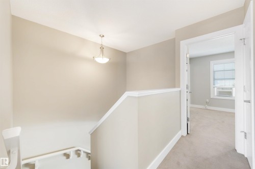 Upper landing with a vaulted ceiling, neutral wall tones, and a pendant light fixture - 2125 24 Street Nw, Edmonton, AB 