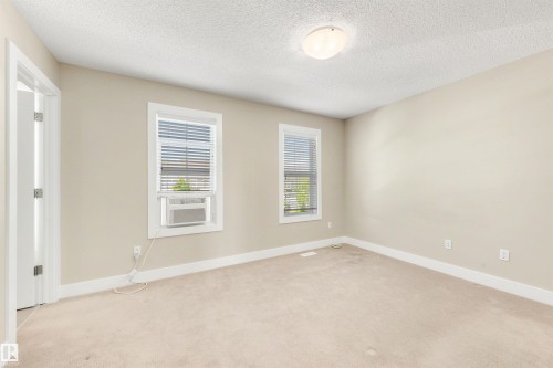 Neutral-toned walls, carpeted flooring, and two windows with blinds - 2125 24 Street Nw, Edmonton, AB 