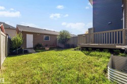 Expansive backyard featuring a manicured lawn, a built-in deck, and a detached shed with a window - 