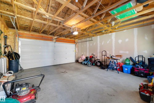 Attached garage featuring concrete flooring, exposed wood beam ceiling, and a paneled overhead door - 2125 24 Street Nw, Edmonton, AB 