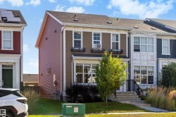 Two-story residential structure with a brown and red siding facade, multiple windows, and a front entrance with steps - 