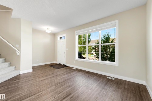 Warm-toned walls with white trim, wood-finish flooring, and a large multi-pane window - 2125 24 Street Nw, Edmonton, AB 