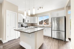 Kitchen featuring white cabinetry, stainless steel appliances, a center island with countertop, wood-finish flooring, and a subway tile backsplash - 