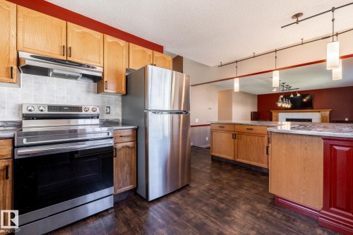 Kitchen featuring wood cabinetry, stainless steel appliances, and a tile backsplash - 89 Ozerna Road Nw, Edmonton, AB 