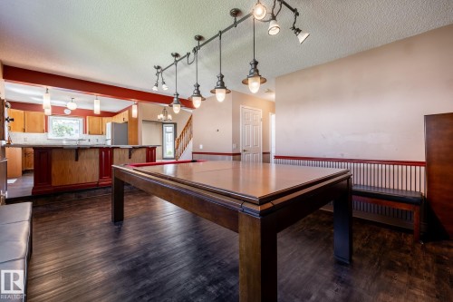 Wood-finish flooring throughout, featuring a built-in bar with wood cabinetry and a stone-finish countertop - 89 Ozerna Road Nw, Edmonton, AB 