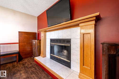 Wood-finish flooring with a fireplace featuring a tiled hearth and a wood surround - 89 Ozerna Road Nw, Edmonton, AB 