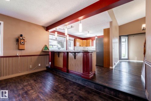 Built-in bar with wood-finish paneling, wood-finish flooring, accent wall paneling, and a vaulted ceiling - 89 Ozerna Road Nw, Edmonton, AB 