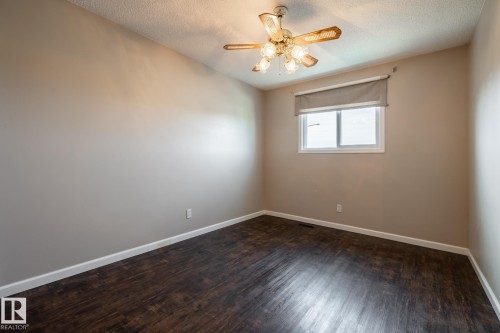 Recessed window with a roller shade, wood-finish flooring, and a ceiling fan with integrated lighting - 89 Ozerna Road Nw, Edmonton, AB 