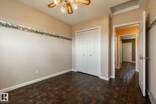 Wood-finish flooring, white bi-fold closet doors, ceiling fan with integrated lighting, and neutral wall tones - 89 Ozerna Road Nw, Edmonton, AB 