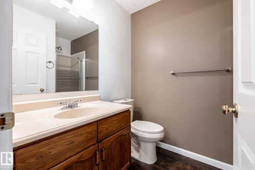 Bathroom with a wood-finish vanity, integrated sink, and chrome fixtures - 89 Ozerna Road Nw, Edmonton, AB 