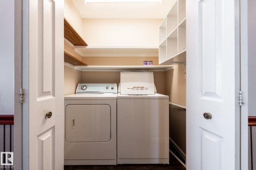 Laundry area featuring built-in shelving, wood-finish shelving, and a paneled door - 89 Ozerna Road Nw, Edmonton, AB 