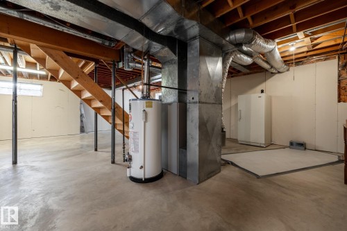 Unfinished basement featuring concrete flooring, exposed wood beam ceiling, open-tread wood staircase, and utility systems - 89 Ozerna Road Nw, Edmonton, AB 