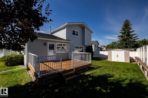 Expansive backyard featuring a wood deck with white railings, a detached storage shed, and a privacy fence - 89 Ozerna Road Nw, Edmonton, AB 