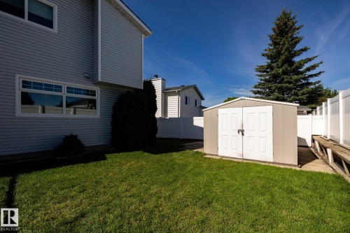 Expansive green lawn with a storage shed, vinyl fencing, and mature evergreen tree - 89 Ozerna Road Nw, Edmonton, AB 