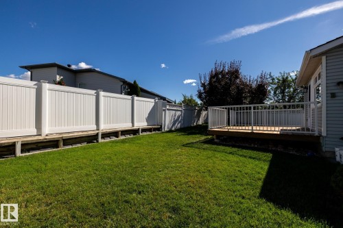 Manicured lawn, white privacy fencing, wood deck, and white deck railings - 89 Ozerna Road Nw, Edmonton, AB 