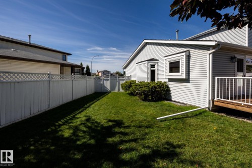 Expansive backyard with a manicured lawn, white privacy fencing with lattice accents, and mature shrubs - 89 Ozerna Road Nw, Edmonton, AB 