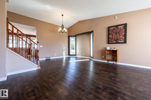 Vaulted ceiling, dark wood-finish flooring, chandelier lighting, wood staircase with banister, and bay window - 89 Ozerna Road Nw, Edmonton, AB 