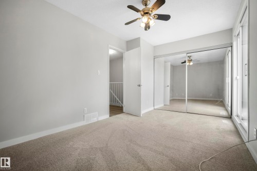 Light-toned carpeting, mirrored closet doors, a ceiling fan with integrated lighting, and a white interior door - 3173 139 Avenue Nw, Edmonton, AB 